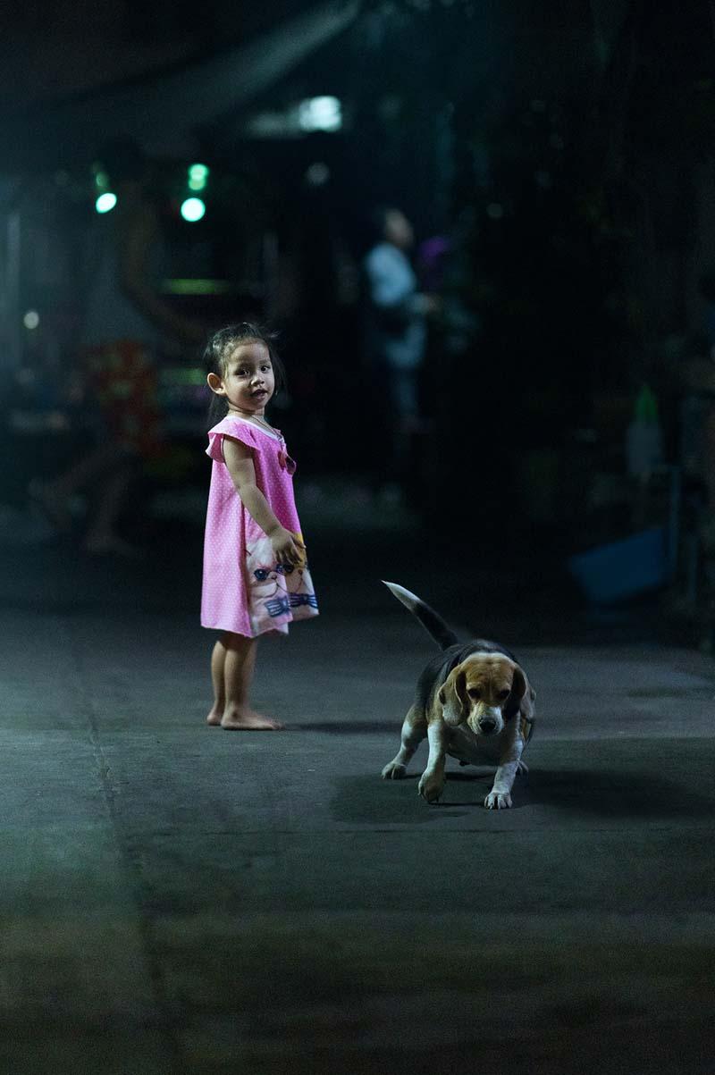 دختربچه‌ای کنار یک سگ در خیابانی در بانکوک