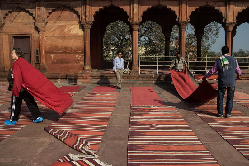 مردان در حال پهن کردن فرش‌های مسجد جامع دهلی در حیاط