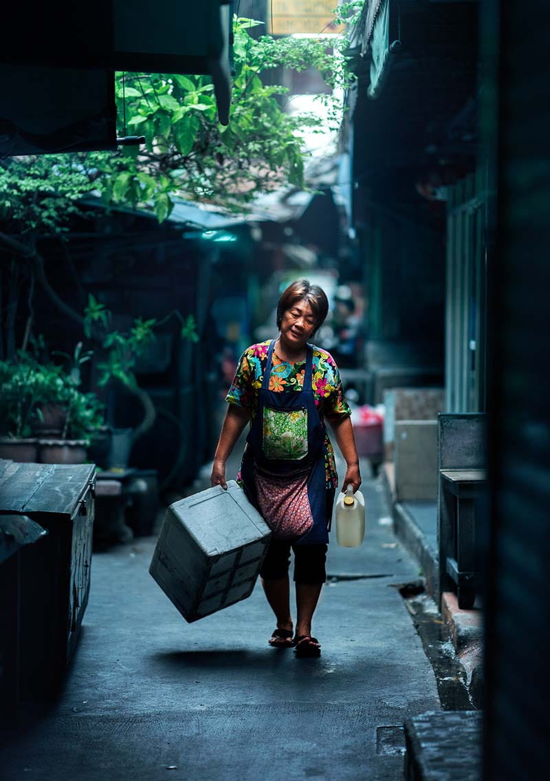 زن تایلندی در حال حمل جعبه‌ای در خیابانی در بانکوک