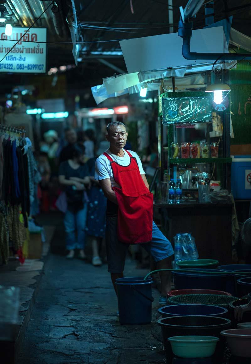 مرد فروشنده با پیش‌بند قرمز در خیابانی در شهر چیانگ مای