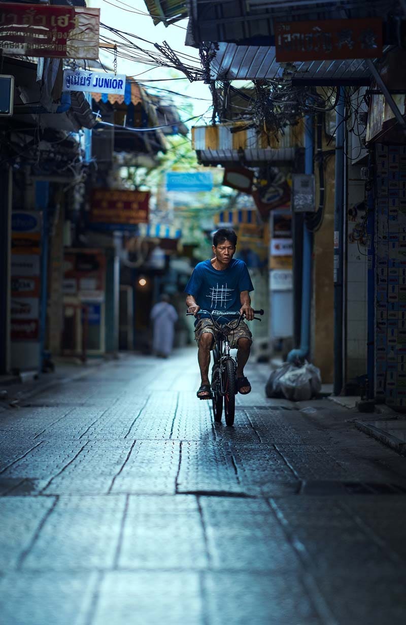 مرد دوچرخه‌ئوار در حال عبور از خیابانی در بانکوک