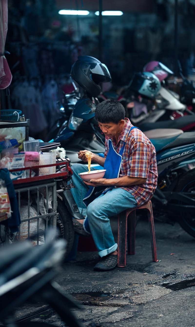 مردی در حال خوردن نودل در خیابانی در شهر چیانگ مای تایلند