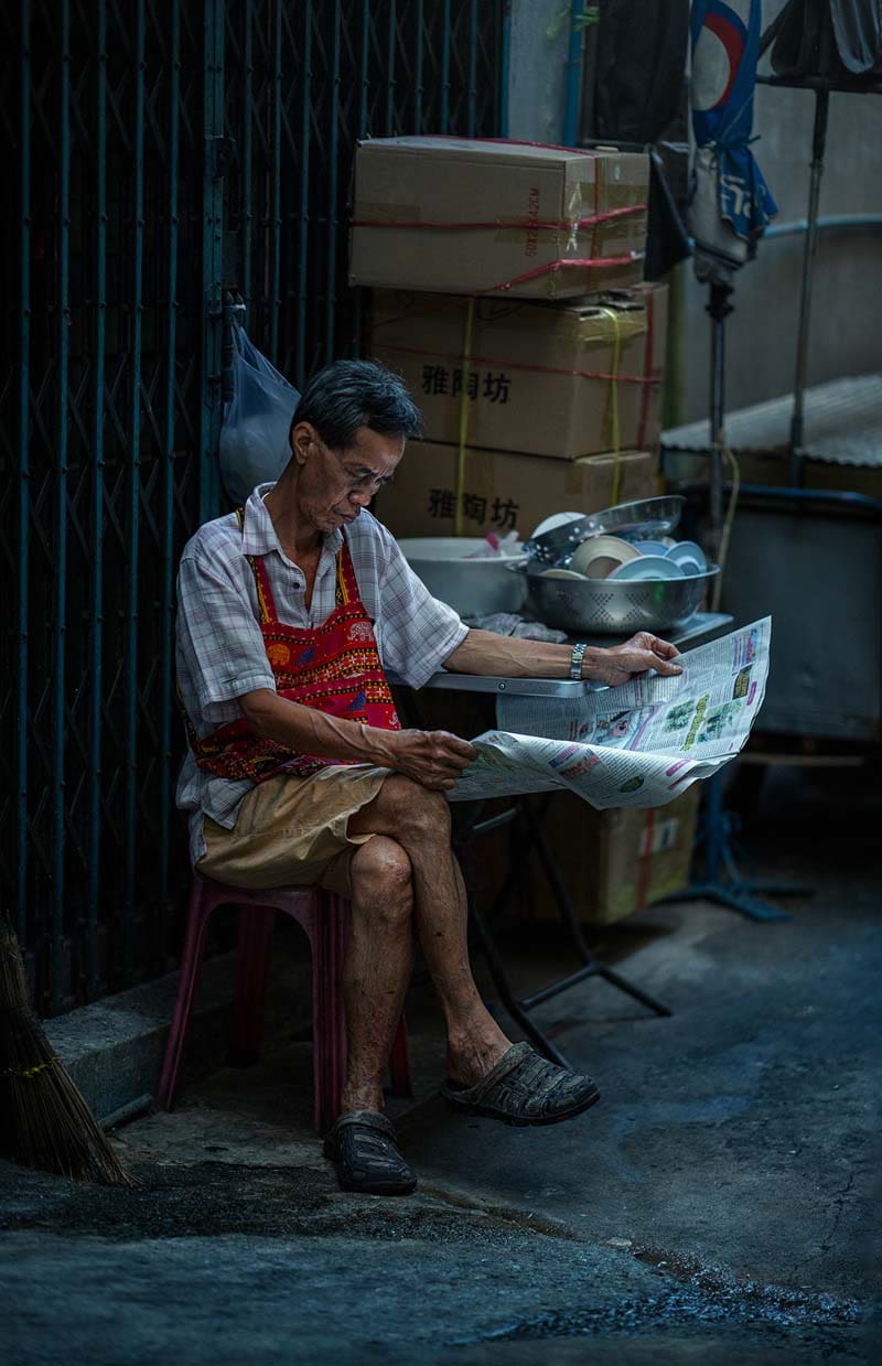 مردی در حال خواندن روزنامه در خیابانی در بانکوک