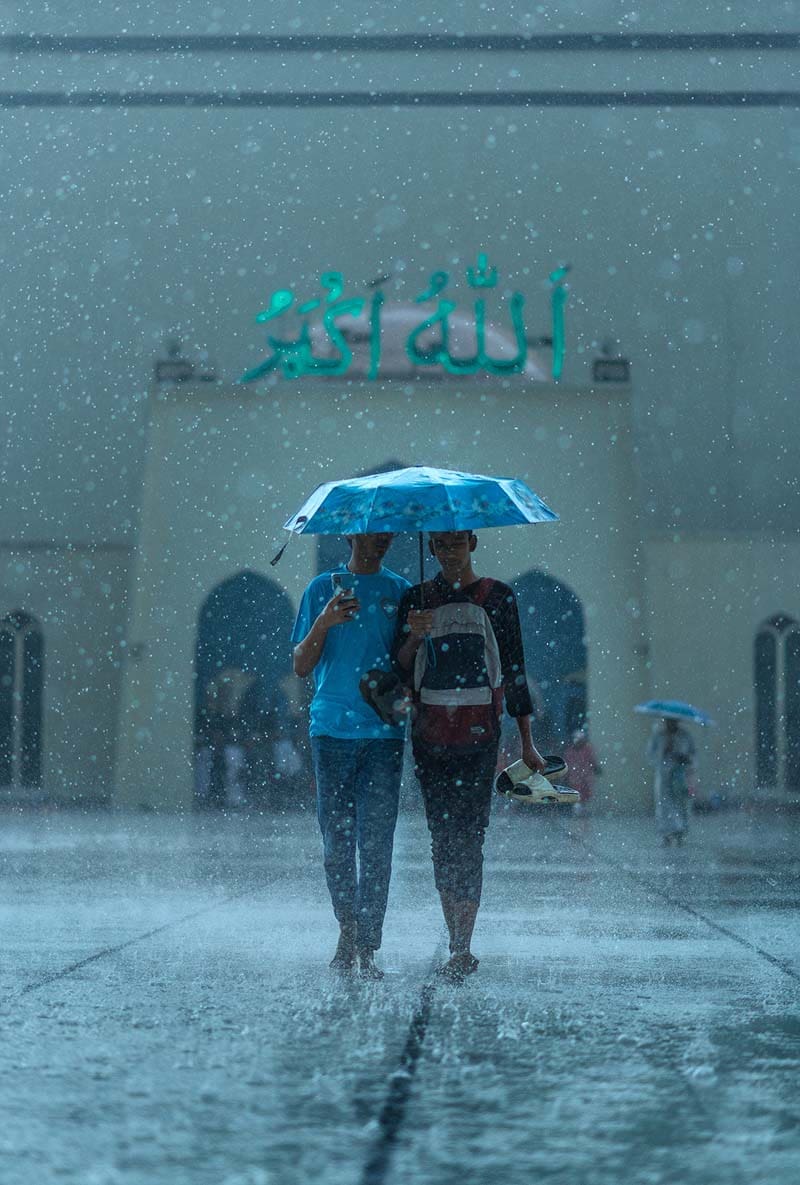 دو نوجوان زیر یک چتر در صحن مسجد