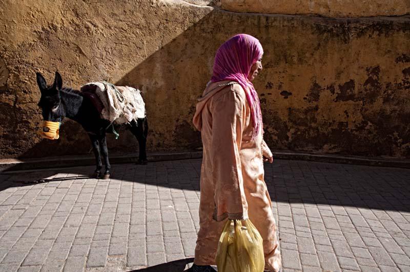 عبور زن مراکشی محجبه با کیسه‌ای در دست از کوچه