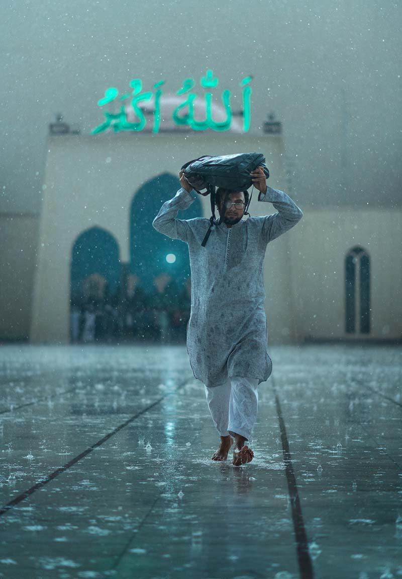 مردی با کیفی بر سر زیر بارش باران