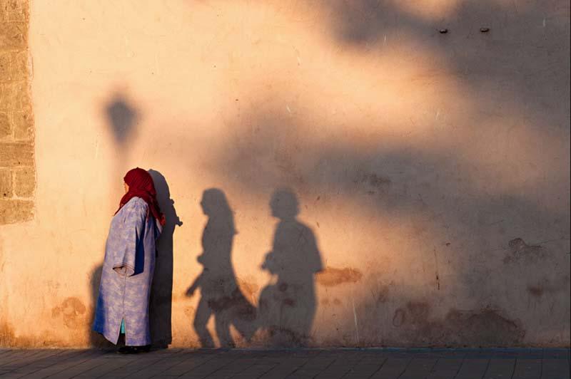 زنی با روسری قرمز کنار دیواری قدیمی در مراکش