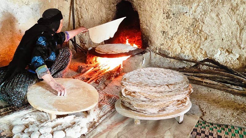 پخت نان محلی توسط بانوی روستایی، منبع عکس: realvillagecooking.ir، عکاس نامشخص