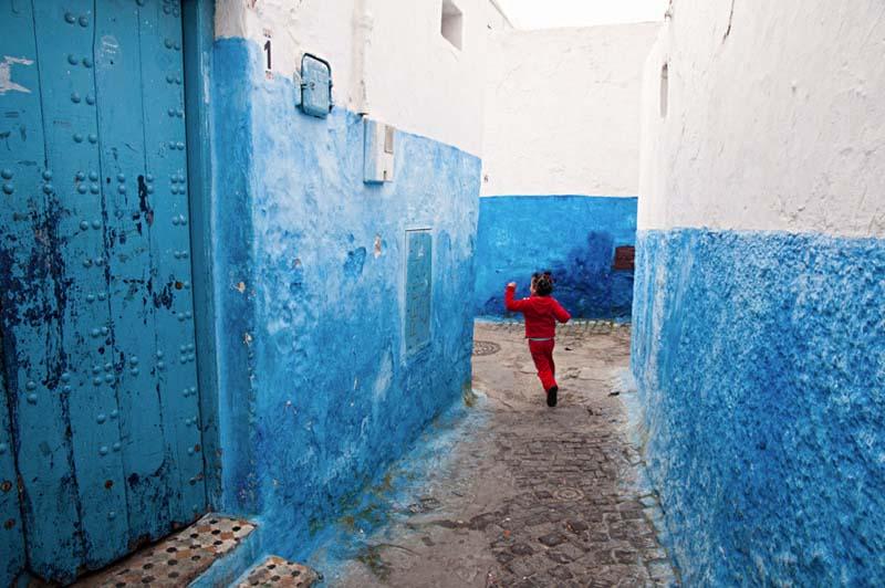دویدن یک کودک مراکشی از میان کوچه‌های باریک آبی رنگ