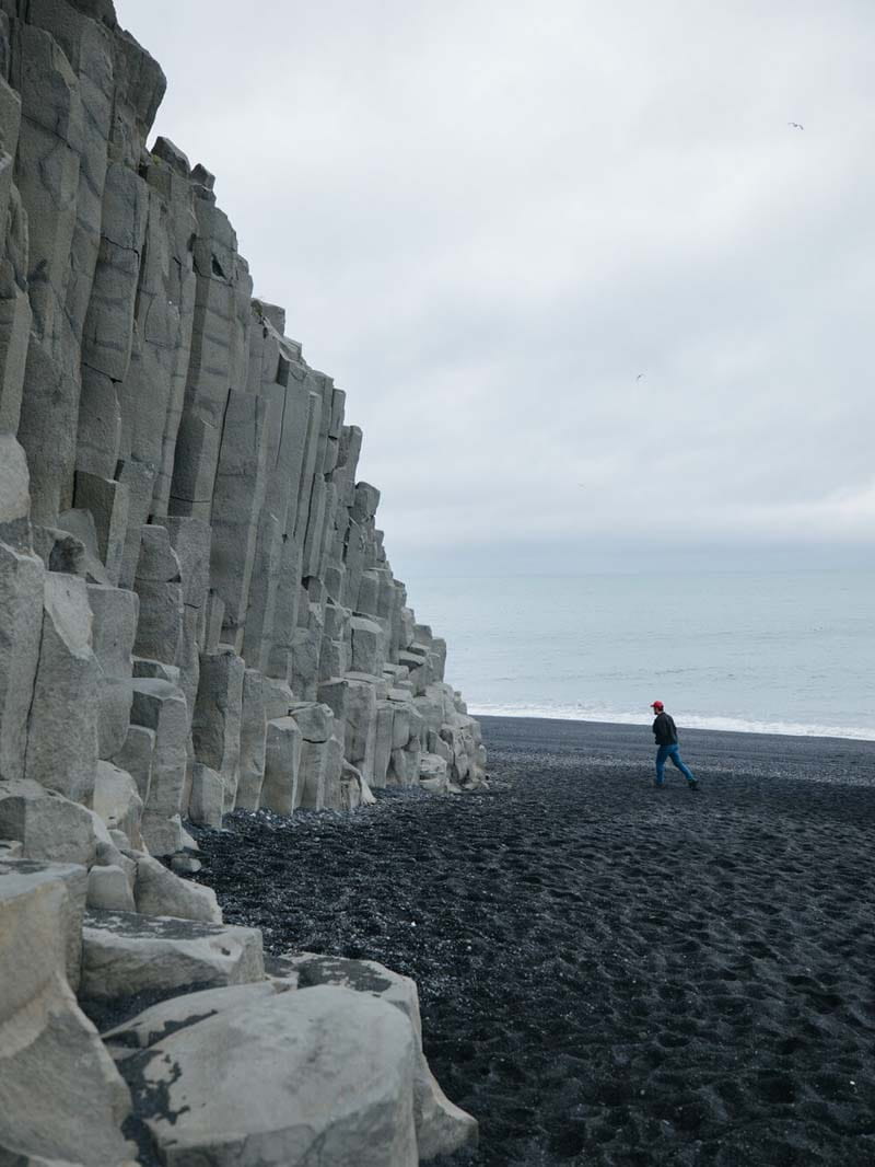 فردی مقابل کوه‌های صخره‌ای ایسلند