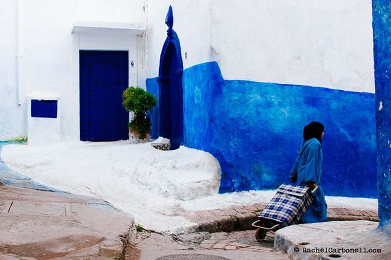 زن عرب با چرخ خرید در کوچه قدیمی و آبی رنگ مراکش
