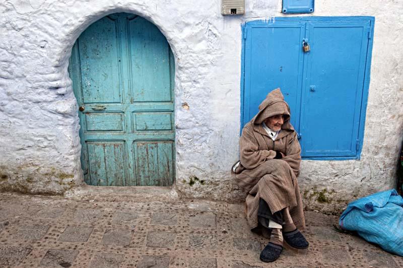 نشستن مرد مراکشی کنار خانه‌ای با درب قدیمی