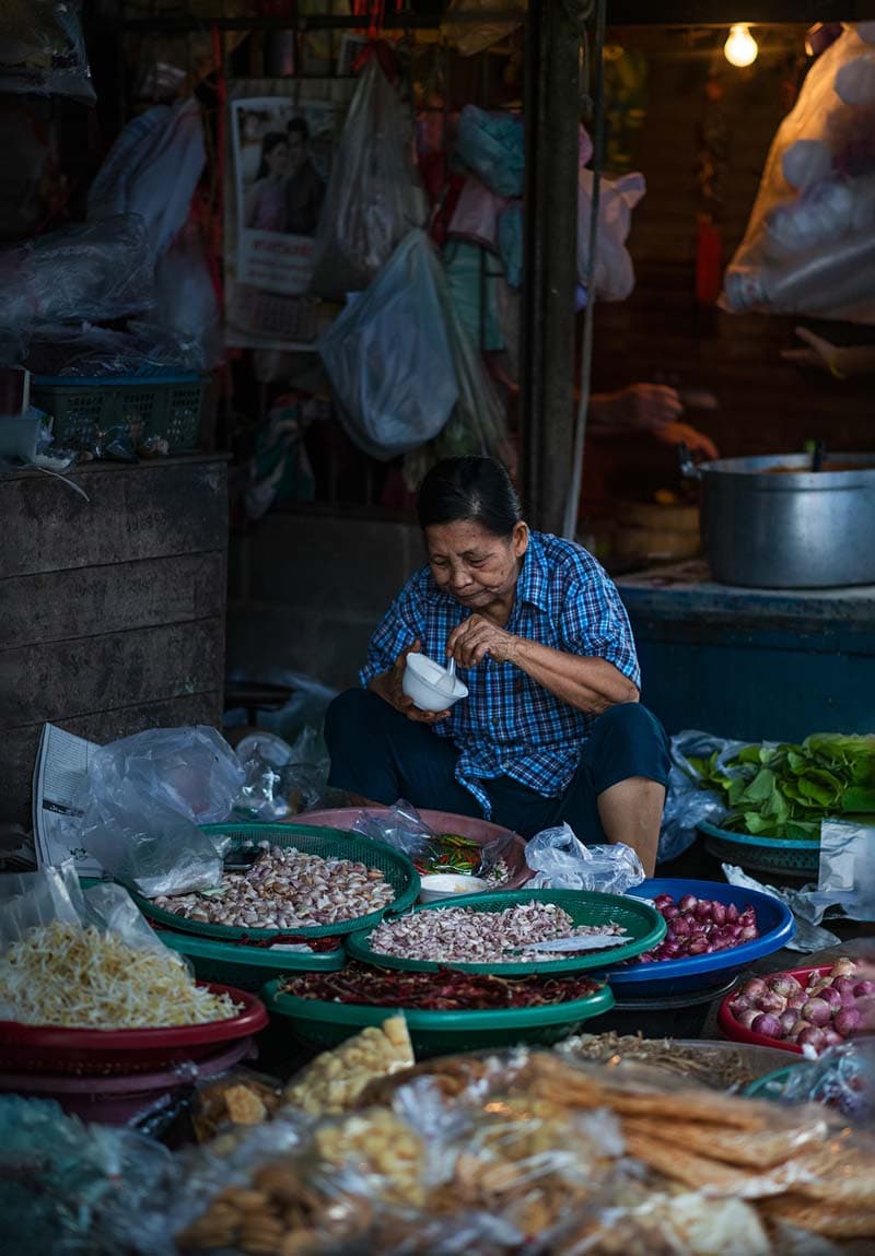 زن فروشنده در حال خوردن غذا در بازار تایلند