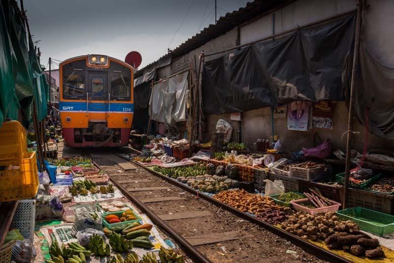 قطاری که از محصولات مختلف در بازار راه آهن تایلند عبور می کند