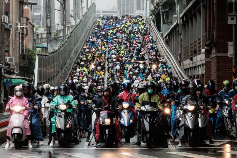 موتور سواران روی پلی در تایپه، تایوان در انتظار تغییر رنگ چراغ راهنما در ابتدای صبح