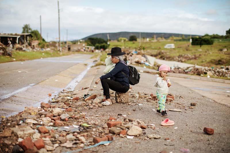 زنی با فرزندانش در میان آوار منطقه ای سیل زده در آفریقای جنوبی